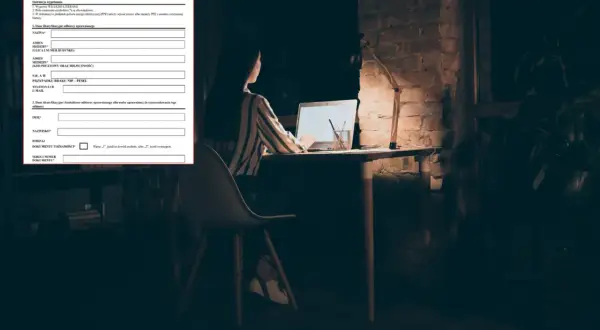Kobieta wypełnia wniosek o zamrożenie cen prądu przy biurku nocą.